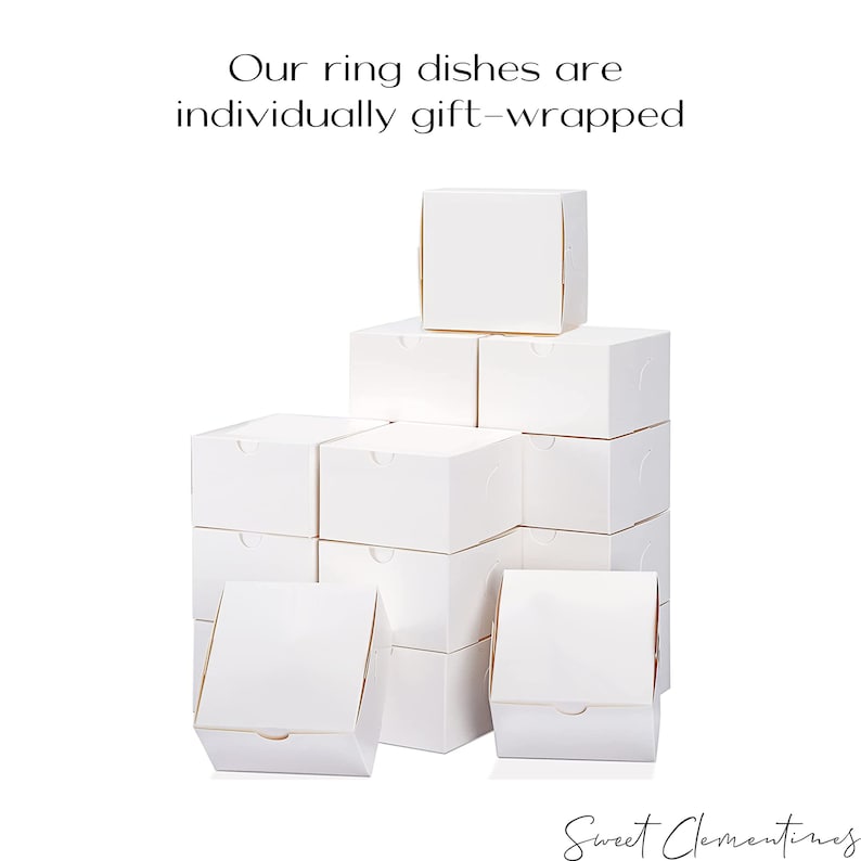 May include: A stack of white cardboard boxes, all the same size, are arranged in a pyramid shape. The boxes are labeled "Sweet Clementines".