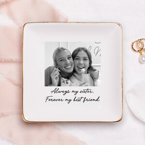 Puede incluir: Un plato cuadrado de cer&aacute;mica blanca con borde dorado. El plato presenta una fotograf&iacute;a en blanco y negro de dos mujeres sonriendo. Debajo de la foto, el texto dice: "Always my sister. Forever my best friend."