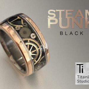 May include: A black titanium ring with a rose gold band and a steampunk design featuring gears and clockwork. The ring is engraved with the text "STEAM PUNK BLACK" and "Titanium Studio 47,867".