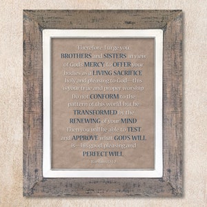 May include: A framed print with a beige background and white frame. The print features a quote from the Bible, Romans 12:1-2, in blue text. The quote reads: "Therefore, I urge you, BROTHERS and SISTERS, in view of God's MERCY, to OFFER your bodies as a LIVING SACRIFICE, holy and pleasing to God - this is your true and proper worship. Do not CONFORM to the pattern of this world, but be TRANSFORMED by the RENEWING of your MIND. Then you will be able to TEST and APPROVE what GOD'S WILL is - his good, pleasing and PERFECT WILL. Romans 12:1-2"