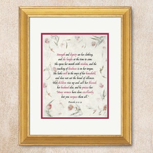 May include: A framed print with a white background and a burgundy border. The print features a floral design with a quote from Proverbs 31:25, "Strength and dignity are her clothing, and she laughs at the time to come. She opens her mouth with wisdom, and the teaching of kindness is on her tongue. She looks well to the ways of her household, and does not eat the bread of idleness. Her children rise up and call her blessed; her husband also, and he praises her: Many women have done excellently, but you surpass them all."