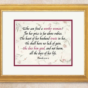 May include: A framed print with a burgundy border and a white background. The print features a quote from Proverbs 31:10-12 about finding a worthy woman. The quote is written in a cursive font and is surrounded by a floral design.