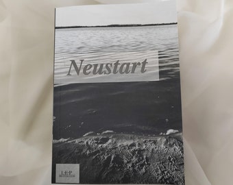 May include: Black and white photo of a lake with the word "Neustart" in gray text on top of the water. The bottom of the image shows a sandy beach with footprints. The text "L-E-P Motivation" is in the bottom left corner.