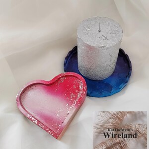 Peut inclure: Un plateau en forme de cœur avec un dégradé de rose et de blanc, orné de paillettes argentées. Une bougie argentée repose sur un plateau bleu festonné. L'image comprend également un petit logo qui dit "KatTheMyth's Wireland."