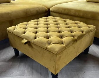 以下が含まれることがあります： マスタードイエローのベルベット製のオットマンで、トップはキルティングされており、黒い木製の脚が付いています。オットマンには収納スペースがあります。