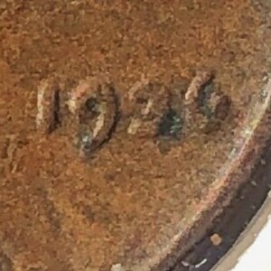 May include: Close-up of a copper-colored penny with the year 1926 stamped on the surface.
