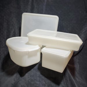 May include: A collection of white plastic food storage containers with lids. The containers are various shapes and sizes, including rectangular and oval. The lids are either solid or clear plastic.