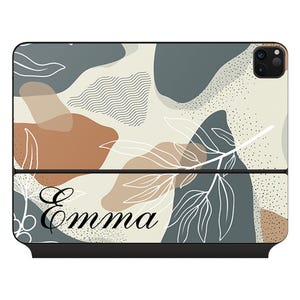 Könnte beinhalten: Eine Handyhülle mit einem abstrakten Design in Beige, Braun und Blau mit Blättern und dem Namen "Emma" unten.