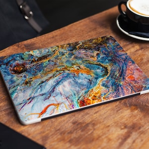 May include: A laptop skin with a colorful abstract design featuring swirling blue, gold, and red hues. The design resembles a marble or agate pattern.
