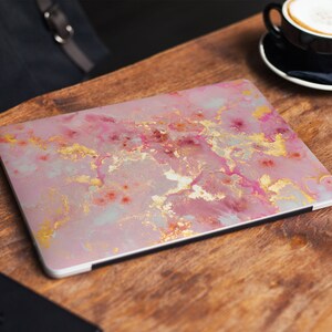 Pode incluir: Uma pele de laptop de m&aacute;rmore rosa e dourado com um padr&atilde;o de redemoinho.