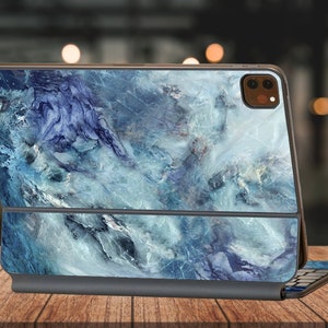 May include: A blue and white marble patterned iPad case with a built-in keyboard. The case is closed and the keyboard is folded up.