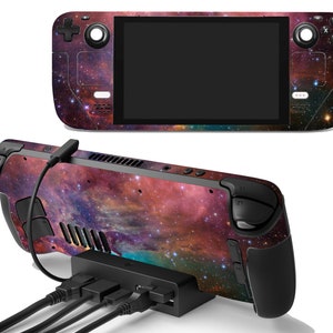 Puede incluir: Una consola de juegos portátil con una piel con temática de galaxia, con una pantalla negra y varios botones. La consola está conectada a una estación de acoplamiento negra con múltiples puertos USB. La piel muestra una vibrante mezcla de tonos rojos, morados y azules.