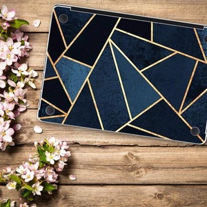 May include: A laptop skin featuring a geometric pattern of dark blue and navy triangles separated by thin gold lines. The rectangular skin has four circular cutouts at the corners and covers the top surface of a closed laptop.