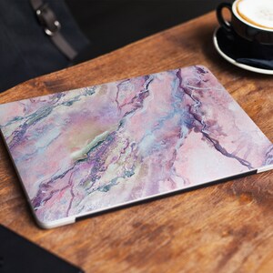 May include: A laptop skin featuring a pink, white and purple marble design. The skin has a glossy finish and is made of durable vinyl.