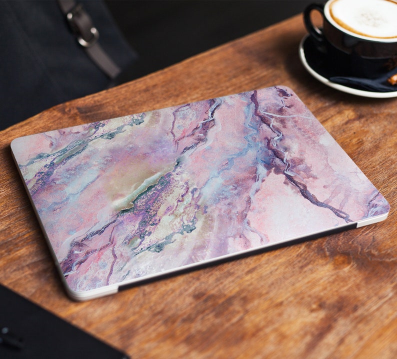 May include: A laptop skin featuring a pink, white and purple marble design. The skin has a glossy finish and is made of durable vinyl.