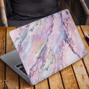 May include: A laptop computer with a pink and purple marble design on the lid. The laptop is open and the keyboard is visible.