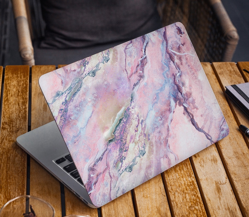 May include: A laptop computer with a pink and purple marble design on the lid. The laptop is open and the keyboard is visible.