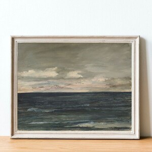 May include: A framed painting of a seascape with a cloudy sky and a dark blue ocean. The painting is in a white frame.