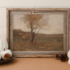 May include: A framed painting of a landscape with a tree in the foreground and a farmhouse in the distance. The painting is in a rustic wooden frame and is surrounded by white pumpkins and pine cones.