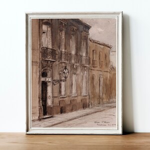 May include: A framed sepia-toned watercolor painting depicting a narrow street in a European city. The buildings are tall and have multiple windows. The street is empty and the sky is overcast.