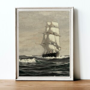 May include: A framed painting of a ship with white sails sailing on a choppy sea. The sky is a light gray with a hint of blue. The ship is in the foreground and the sea is in the background.