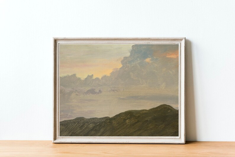 May include: A framed painting depicting a landscape with a cloudy sky and a mountain range in the foreground. The sky is a soft pink and purple, and the clouds are a light grey. The mountains are a dark green.