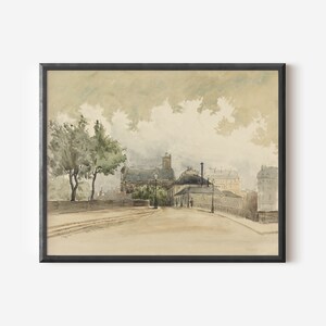 May include: Watercolor painting of a European street scene in a black frame. The artwork depicts a road with buildings, trees, and figures. The color palette is muted with shades of beige, gray, and green, creating a vintage aesthetic.