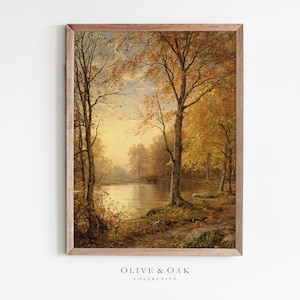 May include: A framed painting of a forest scene with a lake in the foreground. The trees are in autumn colors of yellow, orange, and red. The lake is calm and reflective, with a soft light shining through the trees.