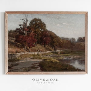 May include: A framed painting depicting a rural landscape with a stream, trees, and a group of cows in the distance. The trees are a mix of green and red, suggesting autumn. The sky is a light blue with some clouds.