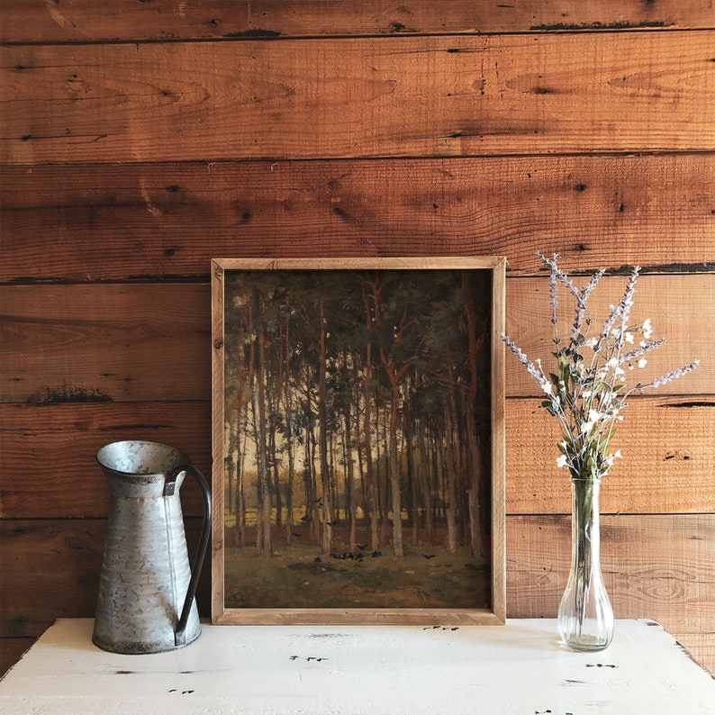 Pu&ograve; includere: Un dipinto incorniciato di una scena di bosco con alberi alti e un sottobosco verde chiaro. Il dipinto &egrave; appeso a una parete di legno con una brocca di metallo e un vaso di fiori secchi di fronte.