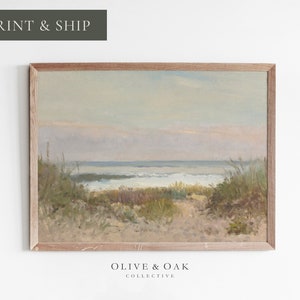 May include: A framed painting depicting a seascape with a path leading to the ocean. The painting features a sandy beach, green grasses, and a blue ocean with white waves. The sky is a light blue with a hint of pink.