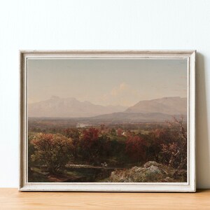 Puede incluir: Una pintura de paisaje enmarcada que representa un valle con una cordillera en el fondo. El valle est&aacute; cubierto de &aacute;rboles con follaje oto&ntilde;al en tonos de rojo, naranja y amarillo. Las monta&ntilde;as son de un azul brumoso en la distancia.