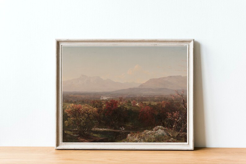 Puede incluir: Una pintura de paisaje enmarcada que representa un valle con una cordillera en el fondo. El valle est&aacute; cubierto de &aacute;rboles con follaje oto&ntilde;al en tonos de rojo, naranja y amarillo. Las monta&ntilde;as son de un azul brumoso en la distancia.