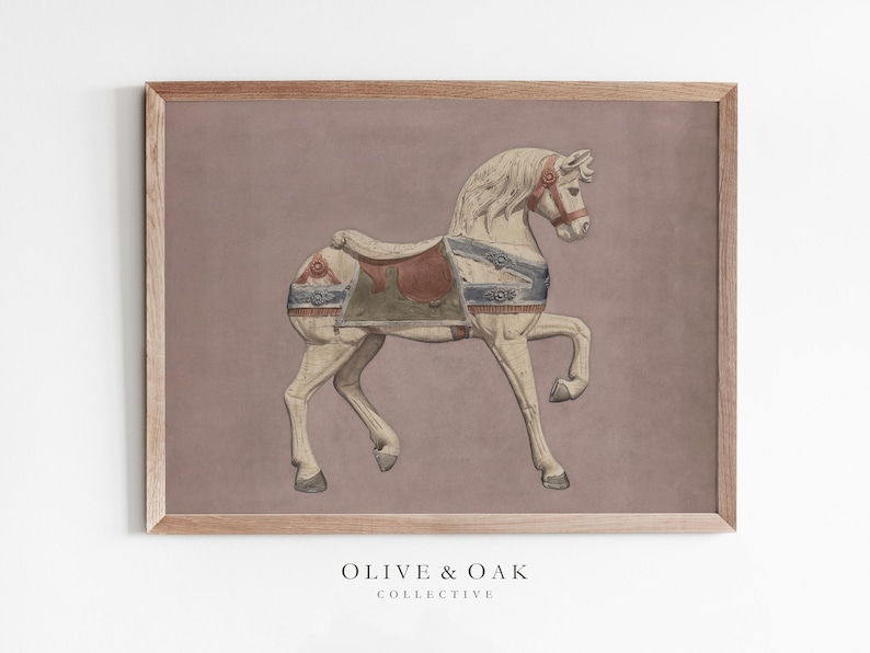 May include: A framed print featuring a vintage carousel horse illustration. The horse is cream-colored with a red and green saddle and blue accents. The background is a muted mauve, and the frame is a light brown. The text "OLIVE & OAK COLLECTIVE" is at the bottom.