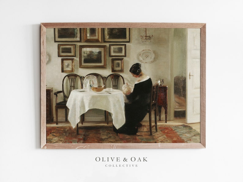May include: A framed vintage painting shows a woman in a black dress seated at a table set for a meal. The room features antique furniture, framed artwork, and a chandelier. The painting is from the Olive & Oak Collective.