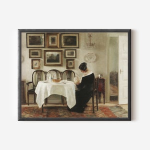 May include: A framed print of a classic interior scene. The artwork depicts a woman in a black dress seated at a table set for a meal. The room features a collection of framed paintings on the wall and antique furniture.