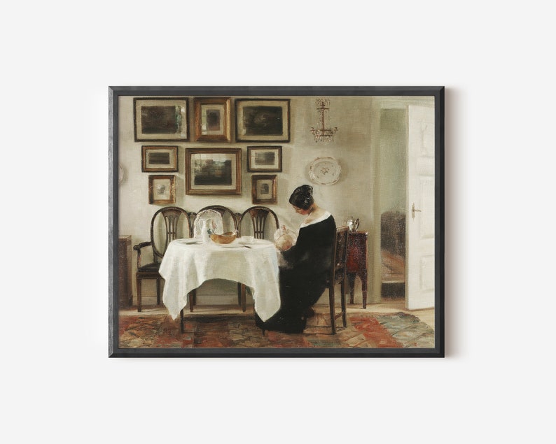May include: A framed print of a classic interior scene. The artwork depicts a woman in a black dress seated at a table set for a meal. The room features a collection of framed paintings on the wall and antique furniture.
