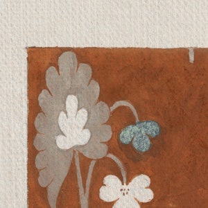 May include: A close-up of a corner of a brown surface with a white and gray floral design. The flowers are stylized and have a simple, elegant look.