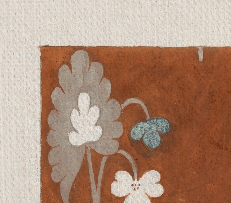 May include: A close-up of a corner of a brown surface with a white and gray floral design. The flowers are stylized and have a simple, elegant look.