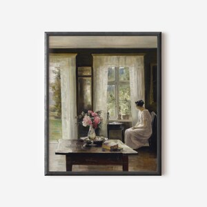 May include: A painting of a woman sitting by a window in a room with white curtains. The woman is wearing a white dress and is looking out the window. There is a vase of pink flowers on a table in front of her.