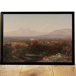 Puede incluir: Una pintura de paisaje enmarcada que representa un valle con monta&ntilde;as en la distancia. El valle est&aacute; cubierto de &aacute;rboles con follaje oto&ntilde;al en tonos de rojo, naranja y amarillo. El cielo es de un azul suave con un toque de rosa.