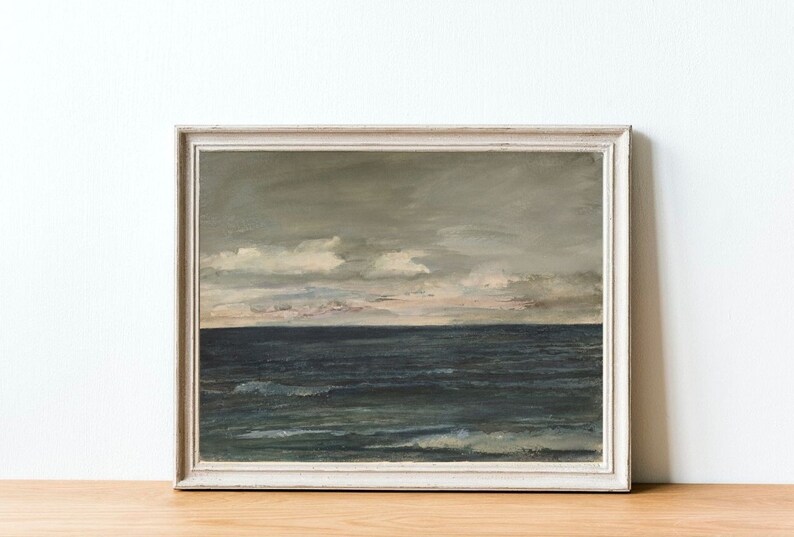 May include: A framed painting of a seascape with a cloudy sky and a dark blue ocean. The painting is in a white frame.