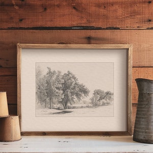 May include: A black and white pencil drawing of a rural landscape with a fence, trees, and a house in the distance. The drawing is framed in a light brown wood frame.