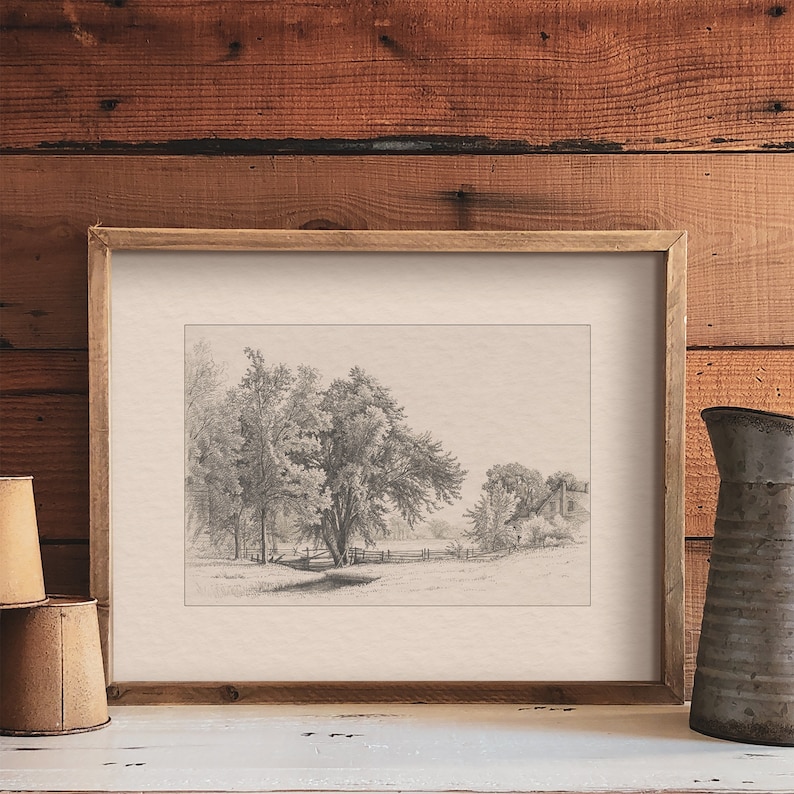 May include: A black and white pencil drawing of a rural landscape with a fence, trees, and a house in the distance. The drawing is framed in a light brown wood frame.
