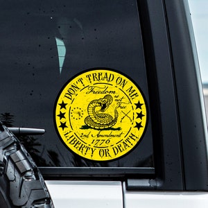 Op de afbeelding: Gele en zwarte "Don't Tread on Me" sticker met een ratelslang, gekruiste pistolen en de tekst "Freedom is not Free, 2nd Amendment 1776, Liberty or Death".