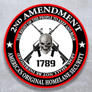 May include: Circular sticker with a black and red border. The text reads "2nd Amendment" and "America's Original Homeland Security." A skull and crossed rifles are in the center, with the number "1789" below.