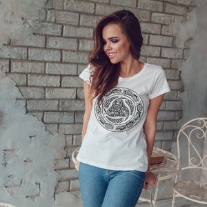 May include: A white t-shirt with a black Celtic knot design. The design is a circle with a knot in the center and a border of intricate patterns.