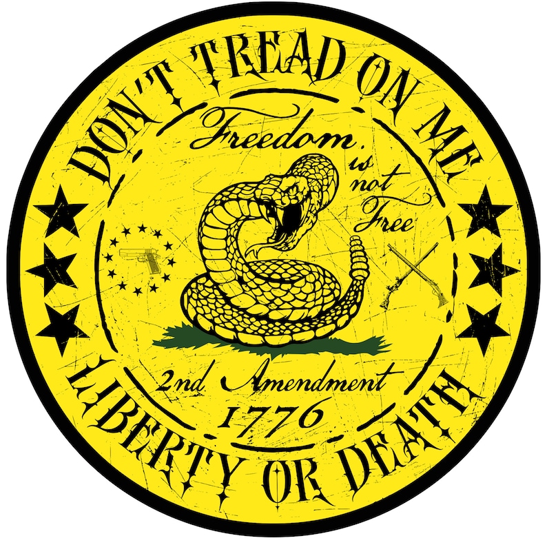 Op de afbeelding: Een gele cirkel met een zwarte rand en de tekst "Don't Tread On Me" in een zwart, verweerd lettertype. Binnen de cirkel bevindt zich een zwarte ratelslang op een groene achtergrond. De tekst "Freedom is not Free" is geschreven in een zwart, verweerd lettertype. De tekst "2nd Amendment 1776" is geschreven in een zwart, verweerd lettertype. De tekst "Liberty or Death" is geschreven in een zwart, verweerd lettertype. Er zijn vijf zwarte sterren rond de cirkel.