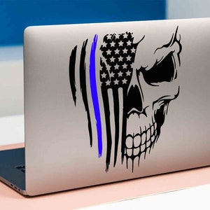 May include: A black and white skull sticker with a blue line and an American flag design. The sticker is on a silver laptop.