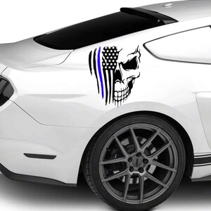 May include: A white car with a black and blue skull and American flag decal on the back fender.